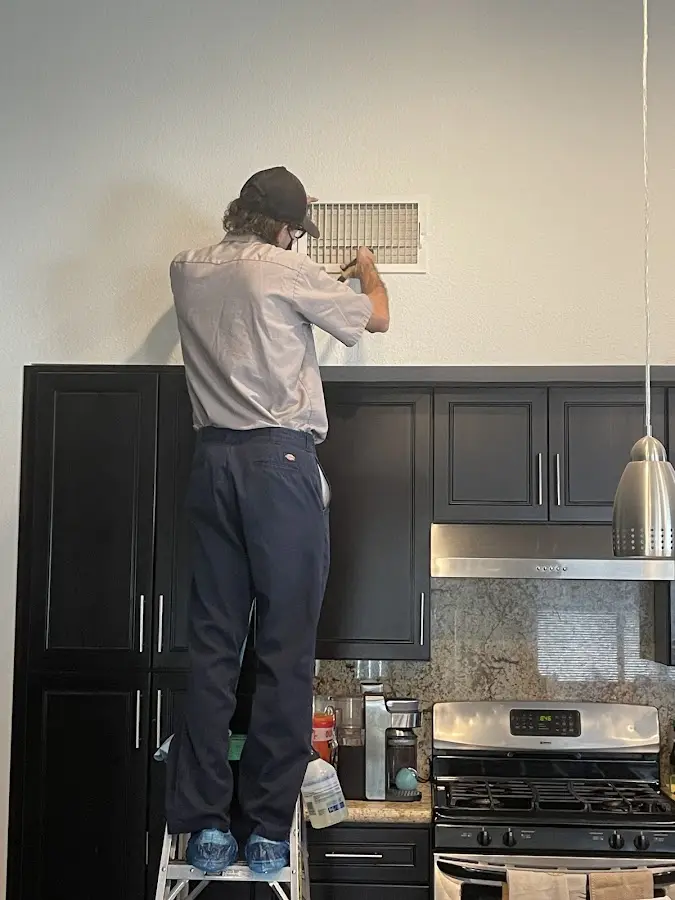 Technician inspecting an air vent during HVAC service in Hastings